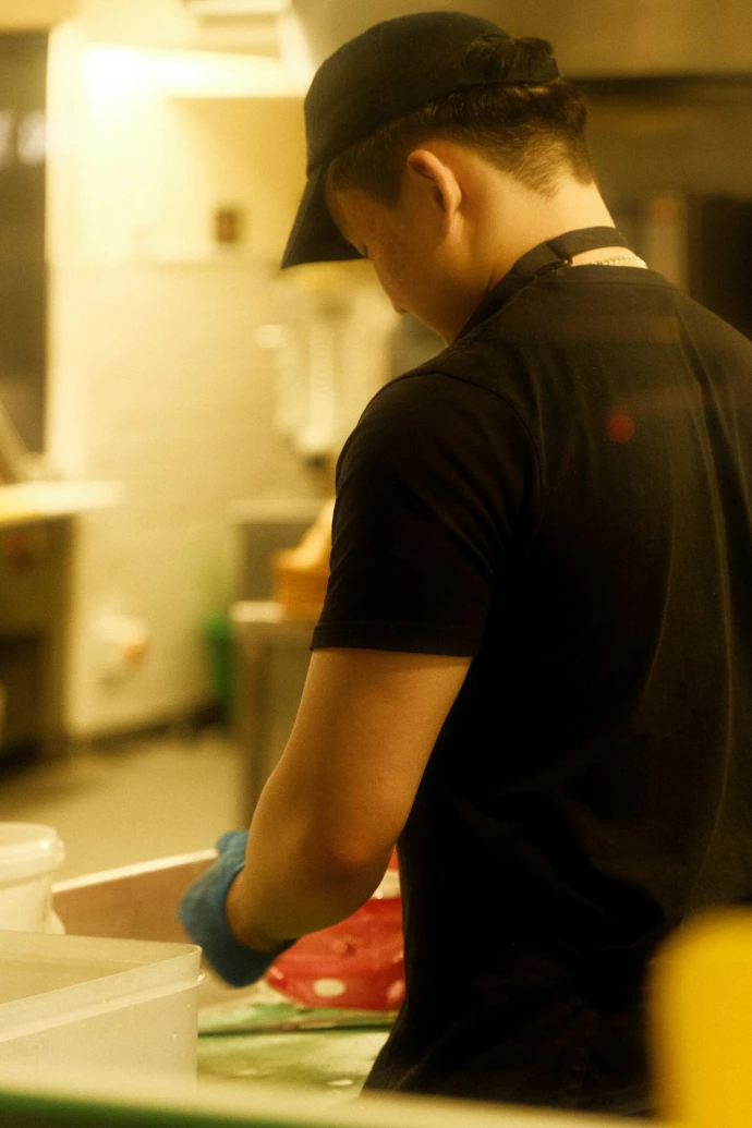 A person in a black t-shirt and cap working.